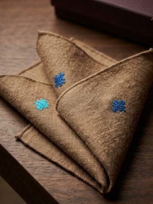 Folded Cervelt pocket square in natural fawn with blue cotton motifs
